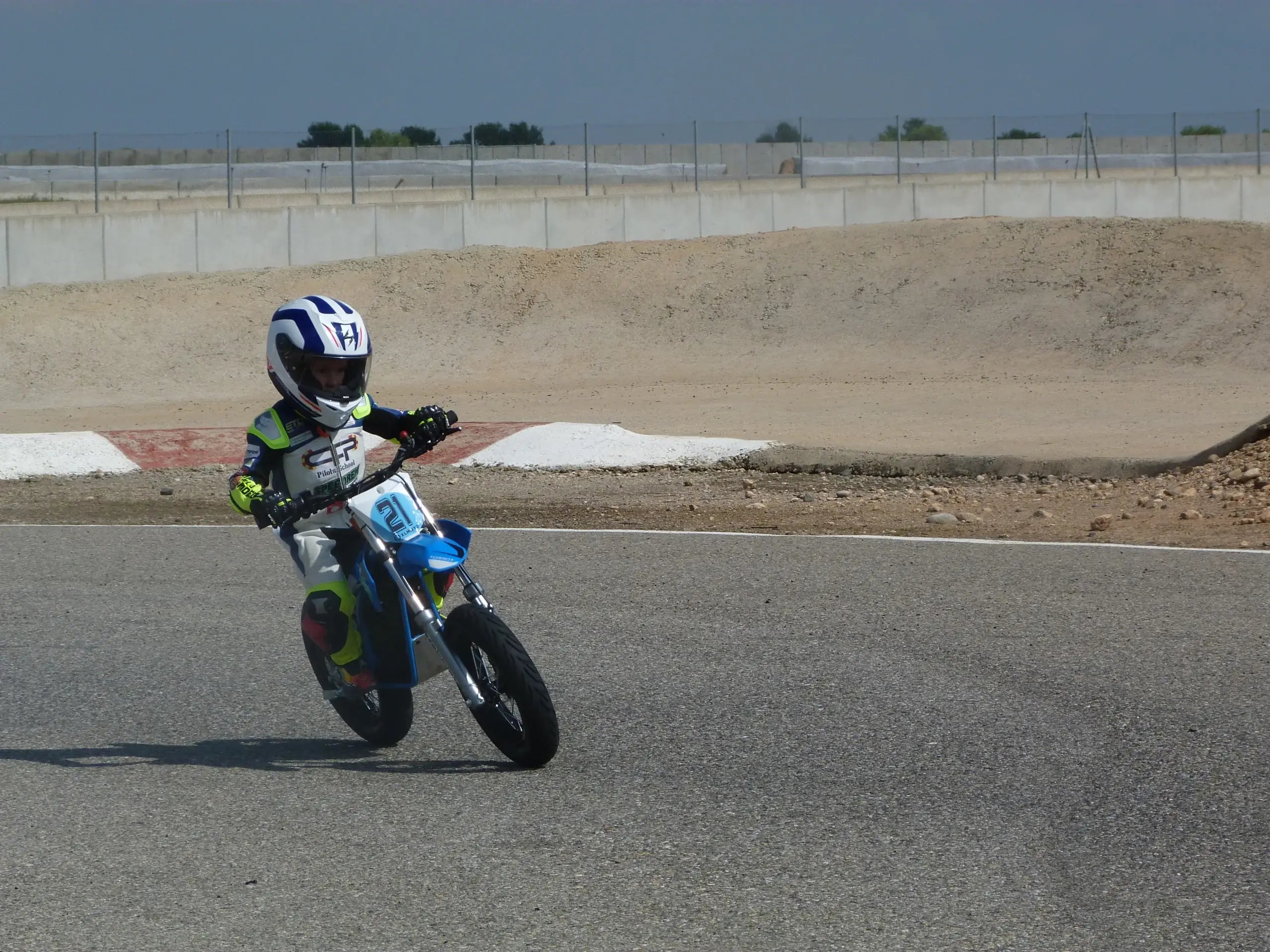 Child on a small bike at a race track with a helmet on