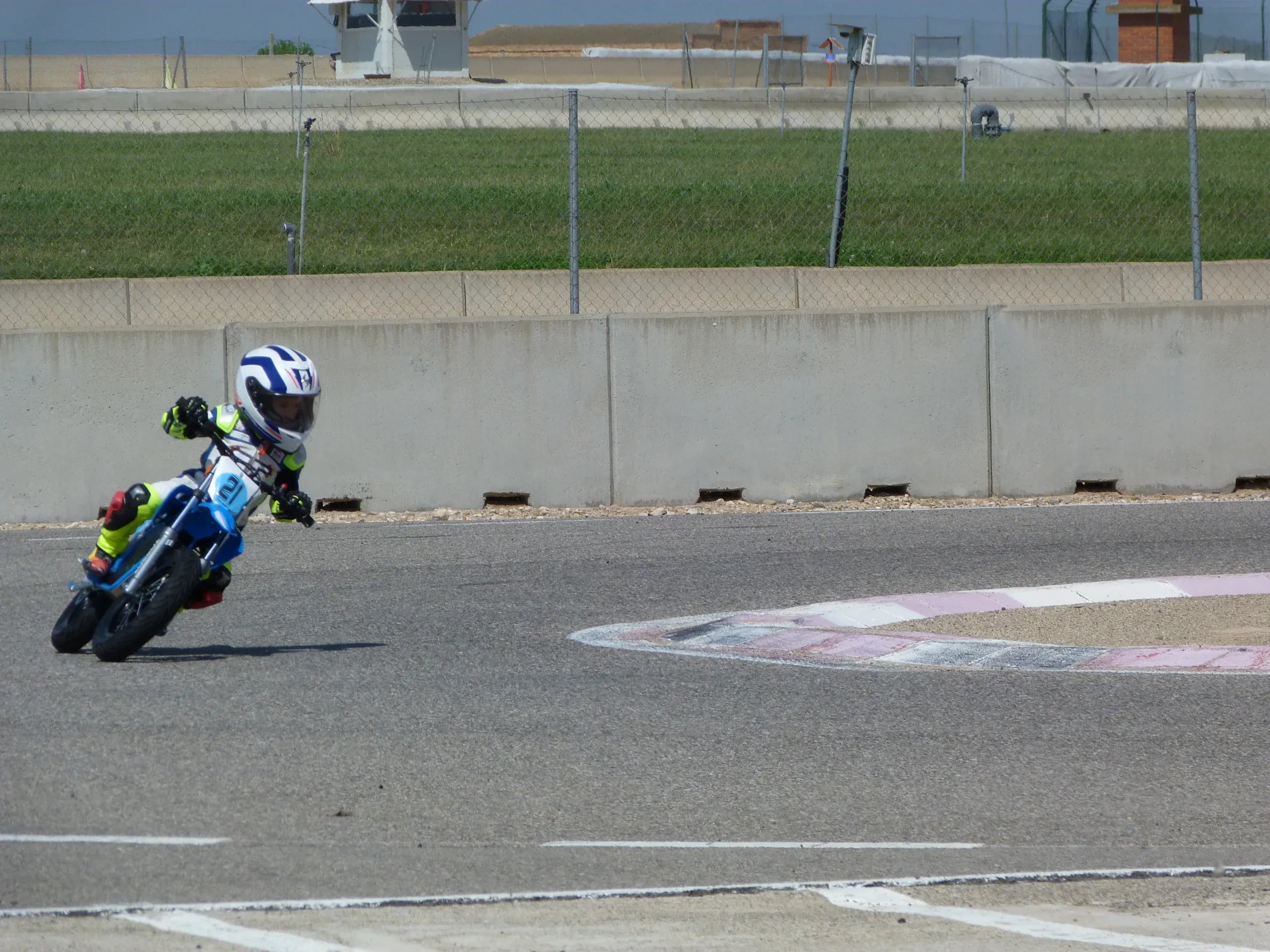 Motorcyclist on a racetrack with a concrete wall and grass in the background