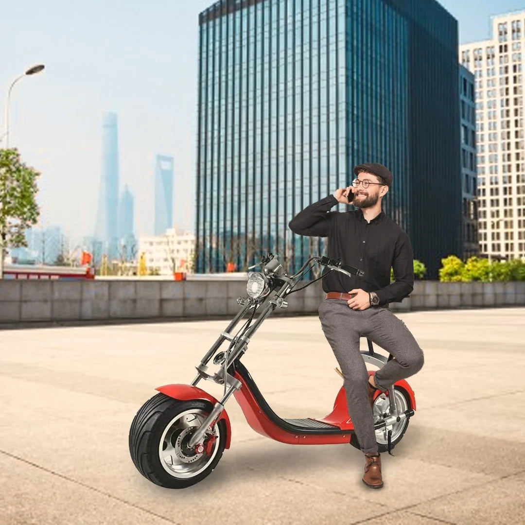 Man sitting on a red scooter in an urban setting with tall buildings in the background