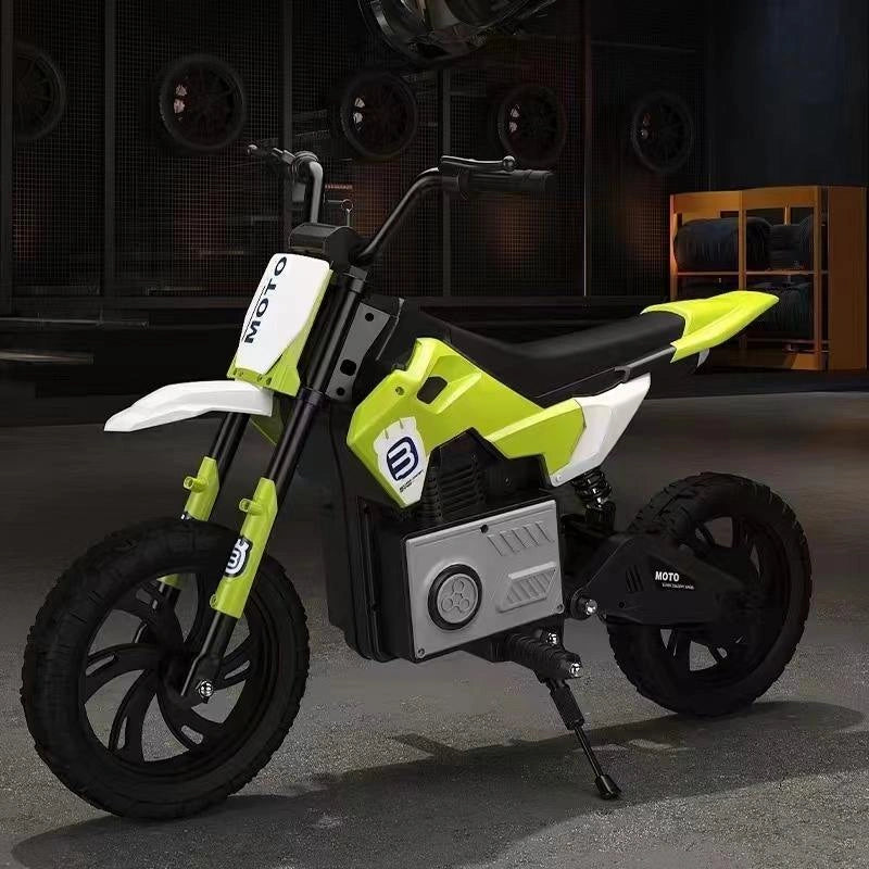 Children's green and black motorcycle in a dark indoor setting