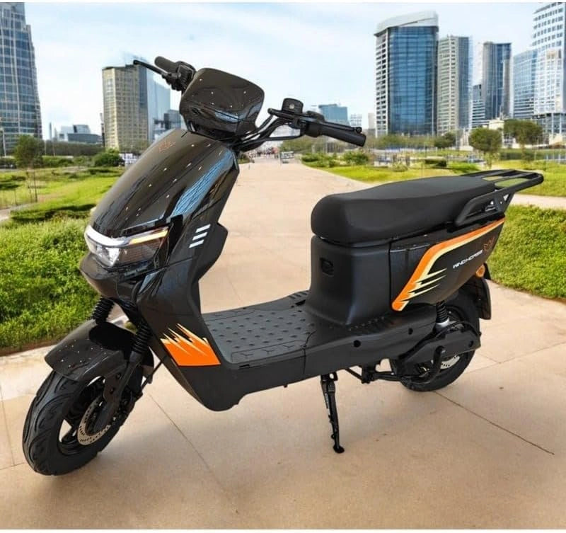 Black and orange electric scooter on a city sidewalk with modern buildings in the background