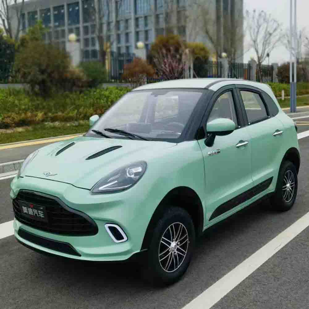 Green compact car on a road with buildings and trees in the background