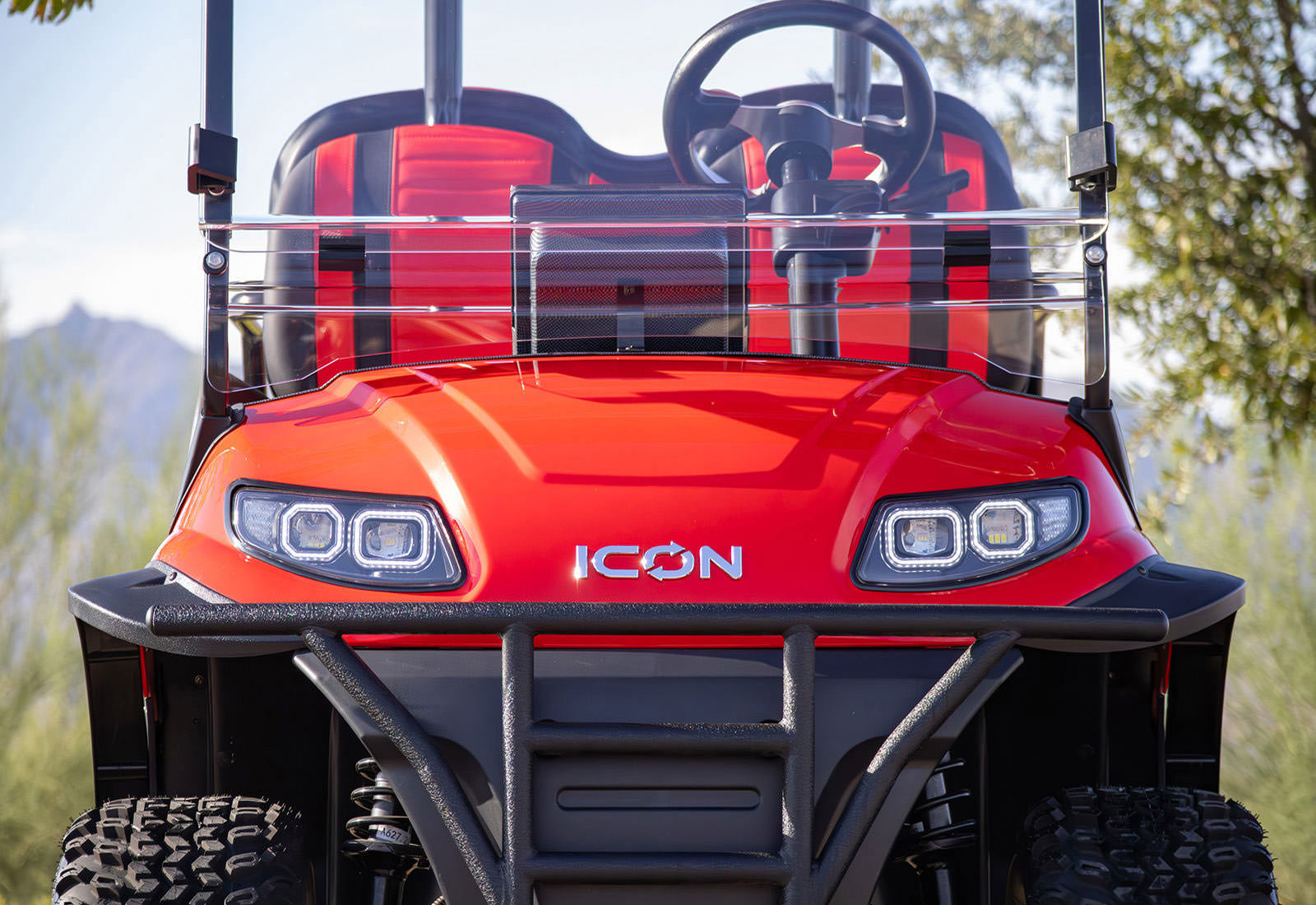 Red ICON golf cart with front view in a natural setting