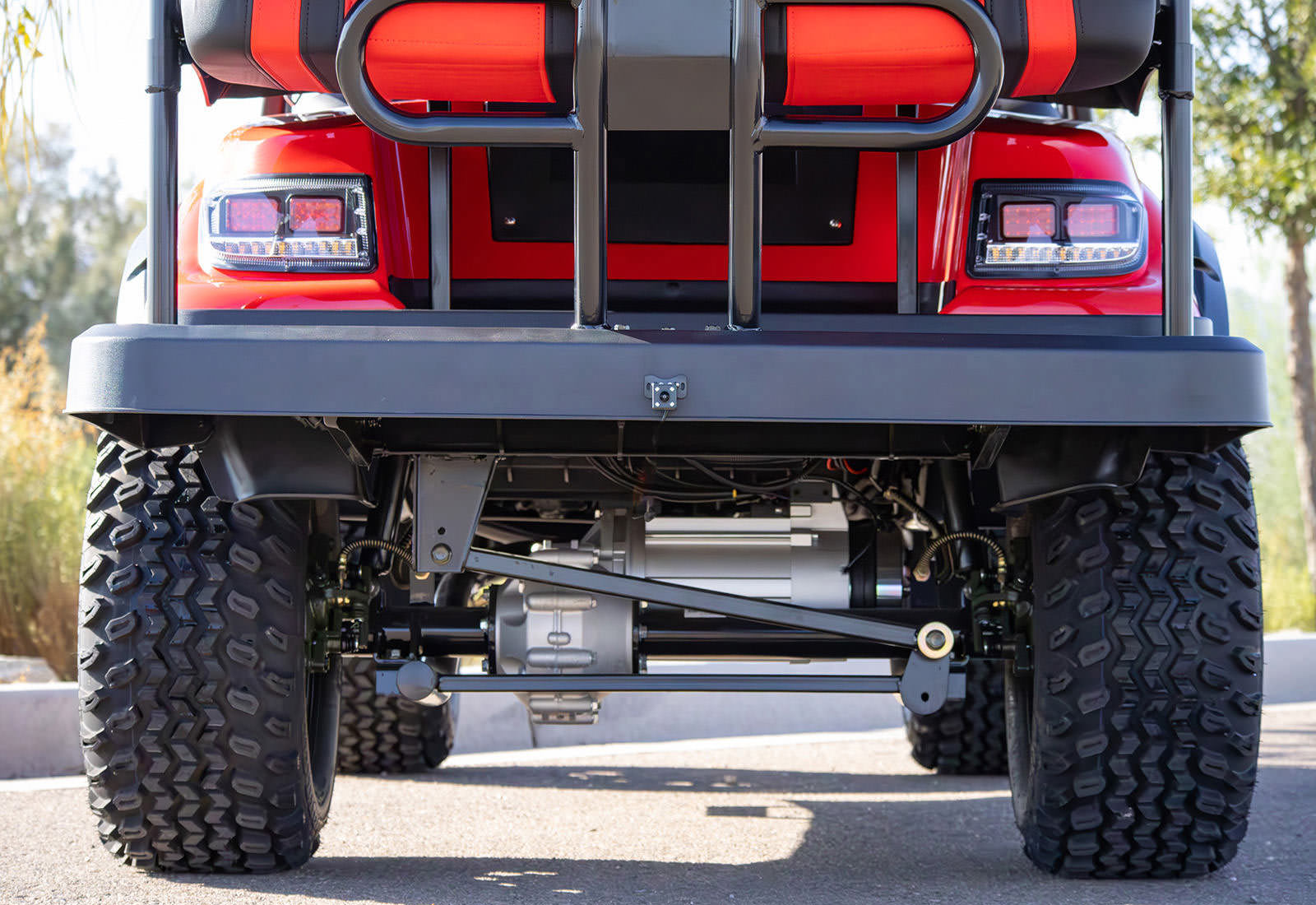 Red golf cart with large black tires on a road