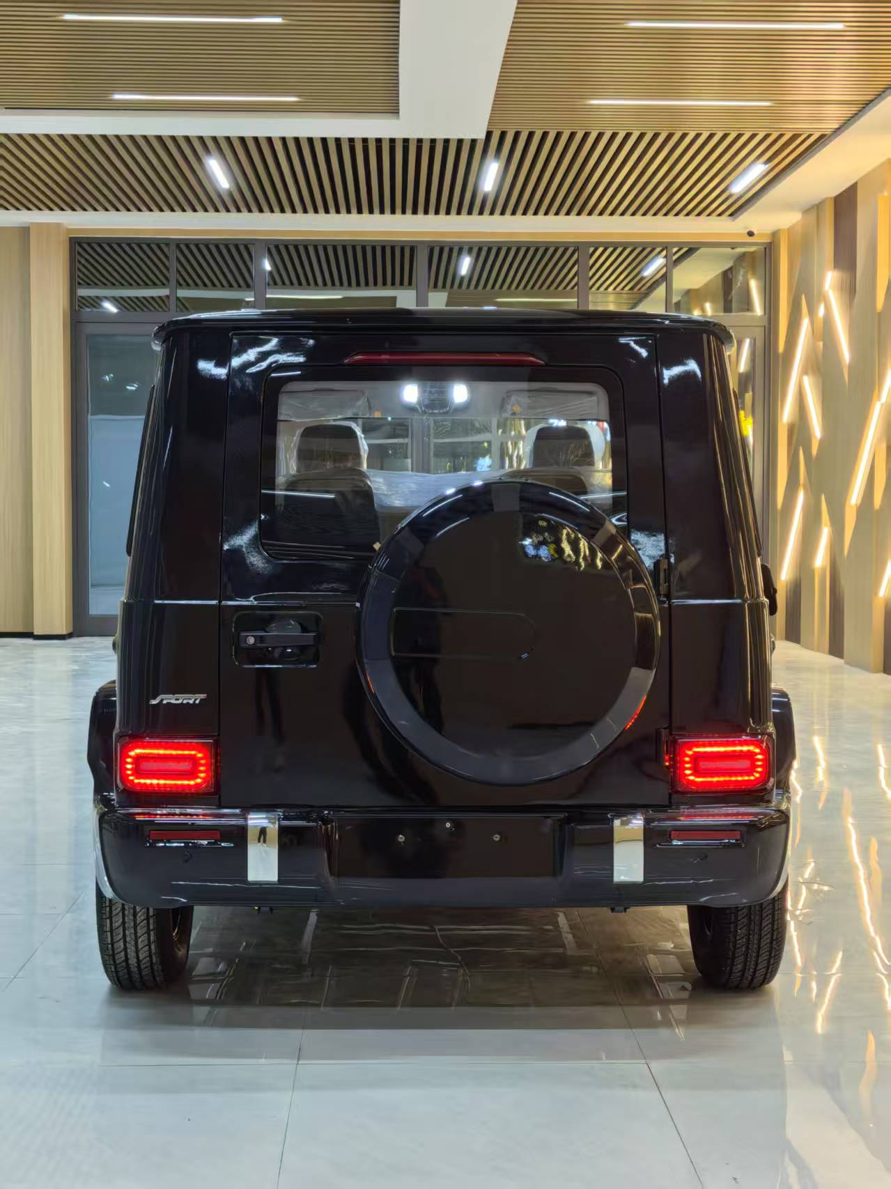 Black SUV in a showroom with wooden ceiling and floor.