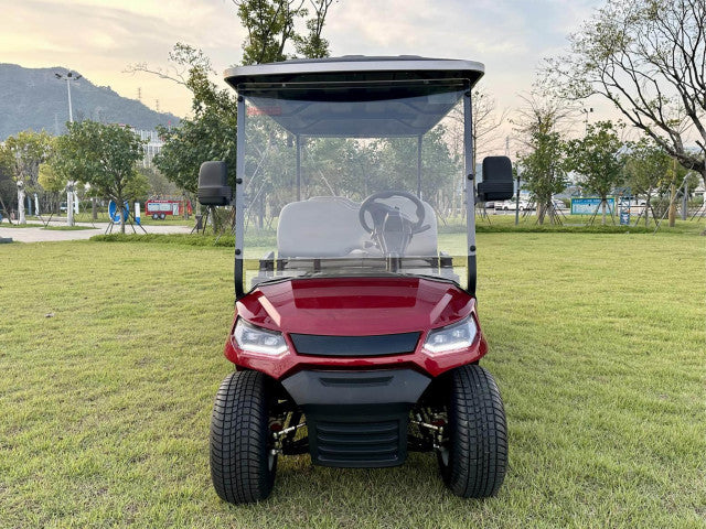 Red golf cart on a grassy area with trees and mountains in the background
