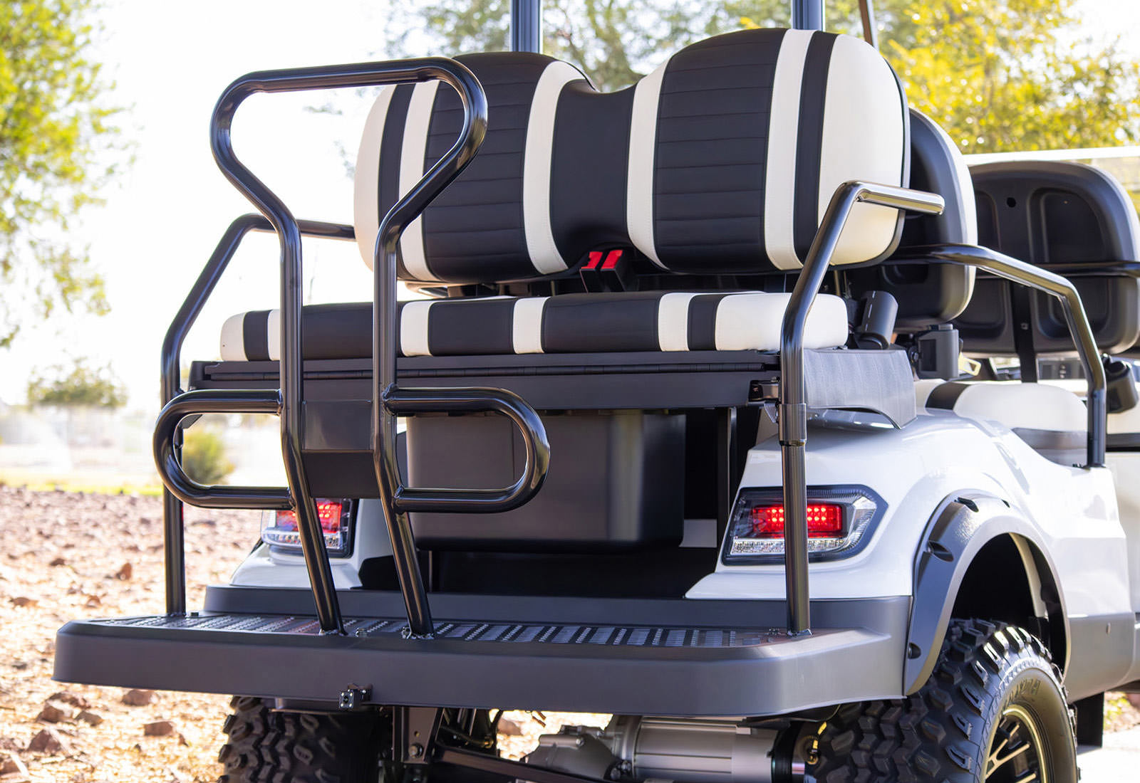 White golf cart with black and white striped seats in an outdoor setting