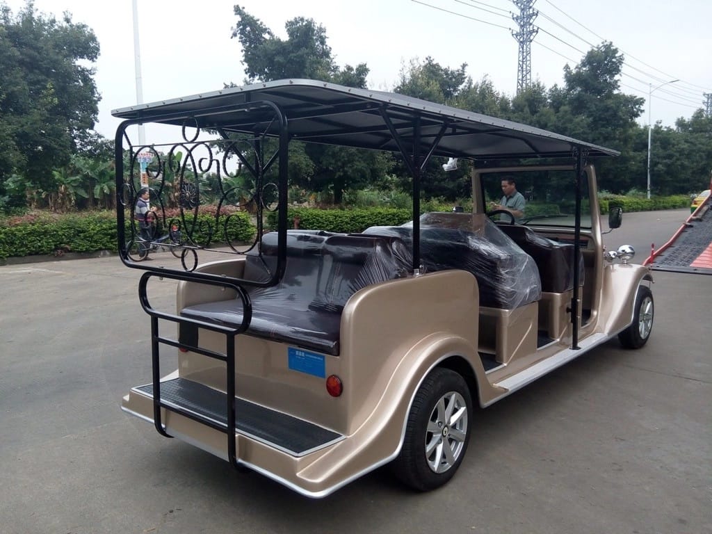 Beige electric vehicle with a canopy on a road with trees in the background