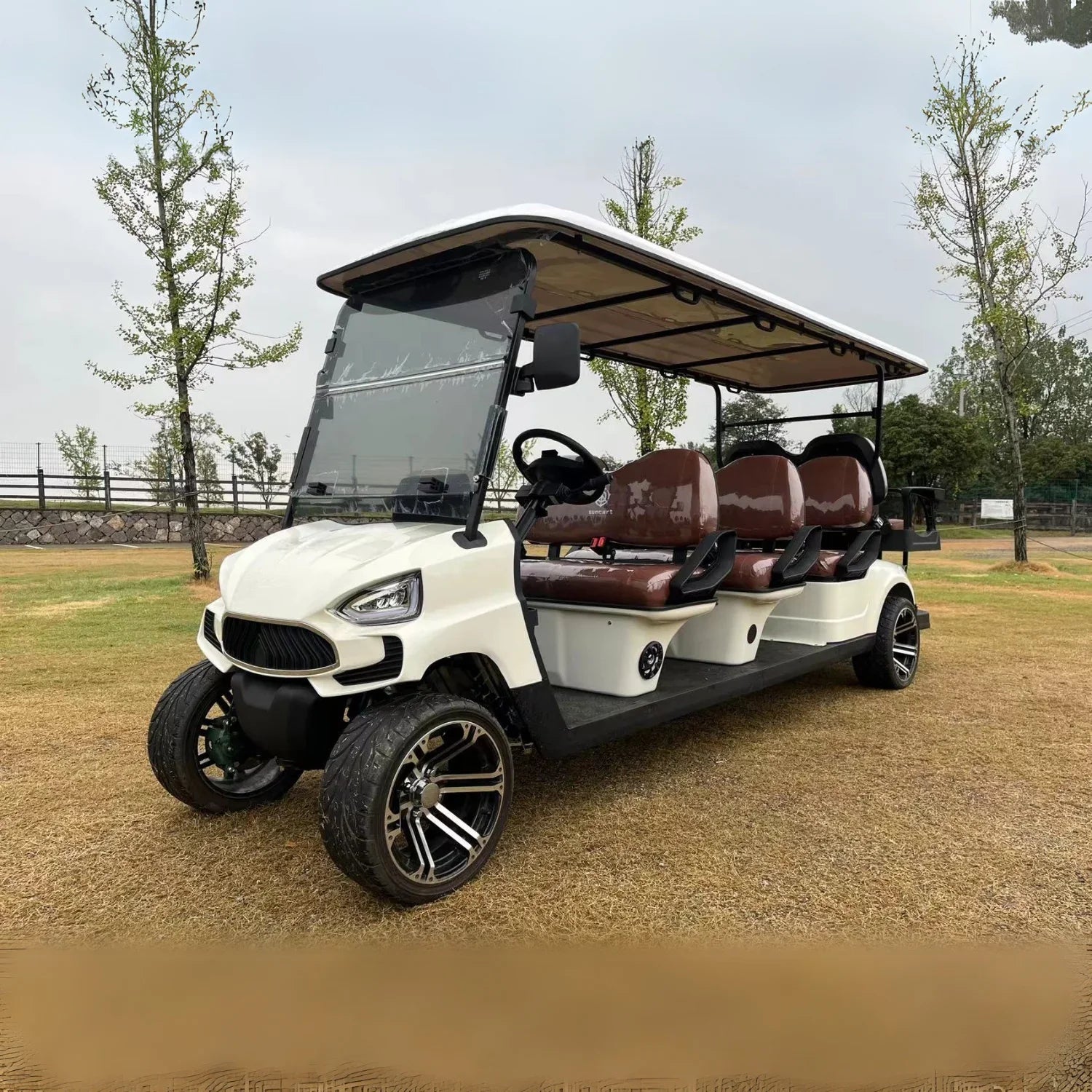 White golf cart with brown seats on a gravel path in a park-like setting