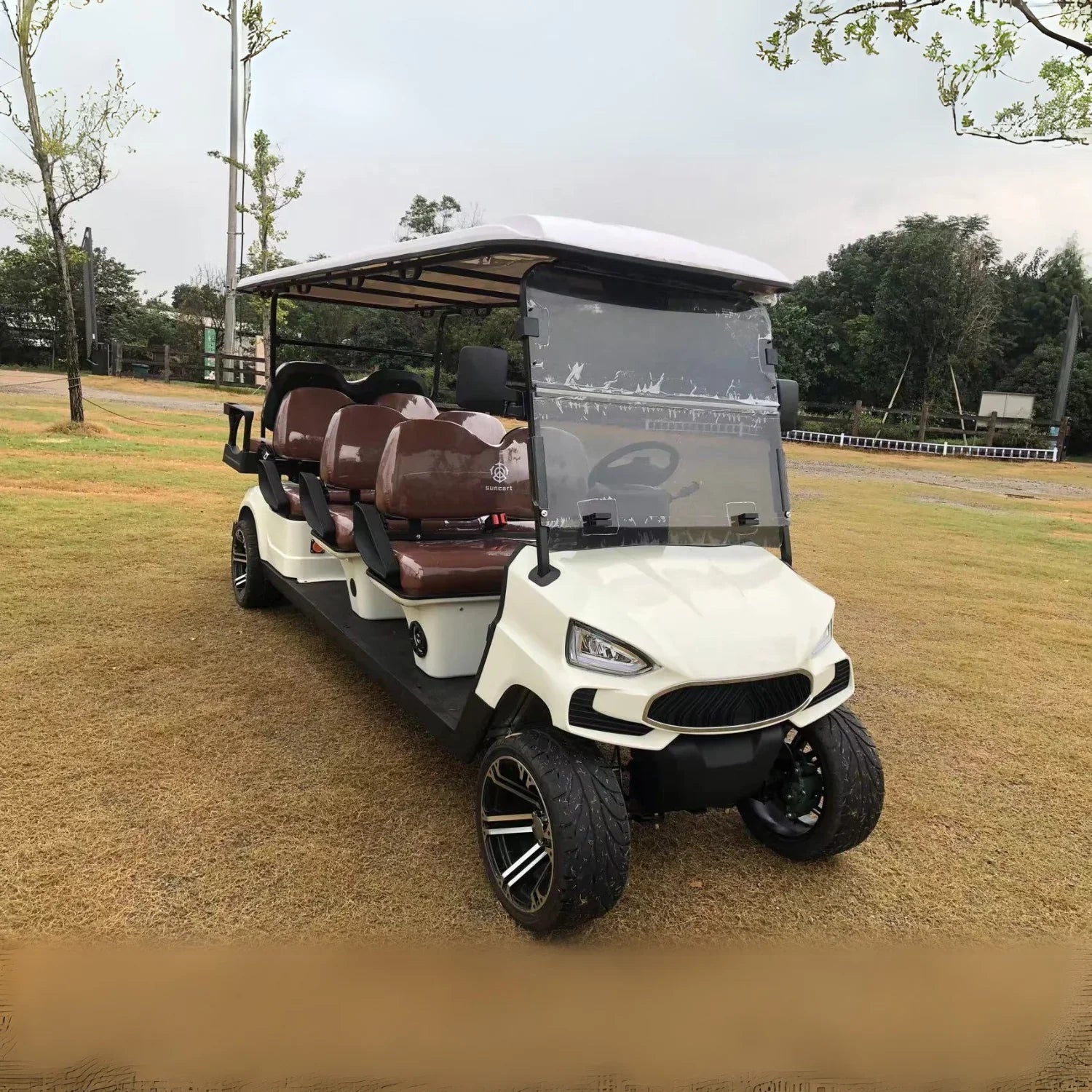 White golf cart with brown seats on a grassy area
