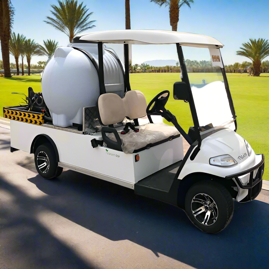 ocean cartz three-quarter front view of a white utility electric vehicle designed as a sprayer or water transport golf cart, parked on an asphalt path in a sunny resort or golf course. This specialized two-seater work cart features a large white spherical water tank and a black and yellow striped rear utility platform holding a pump and hose. The cart has tan seats, a white roof, and custom black and silver wheels, highlighting its function as a maintenance vehicle for irrigation or pest control.