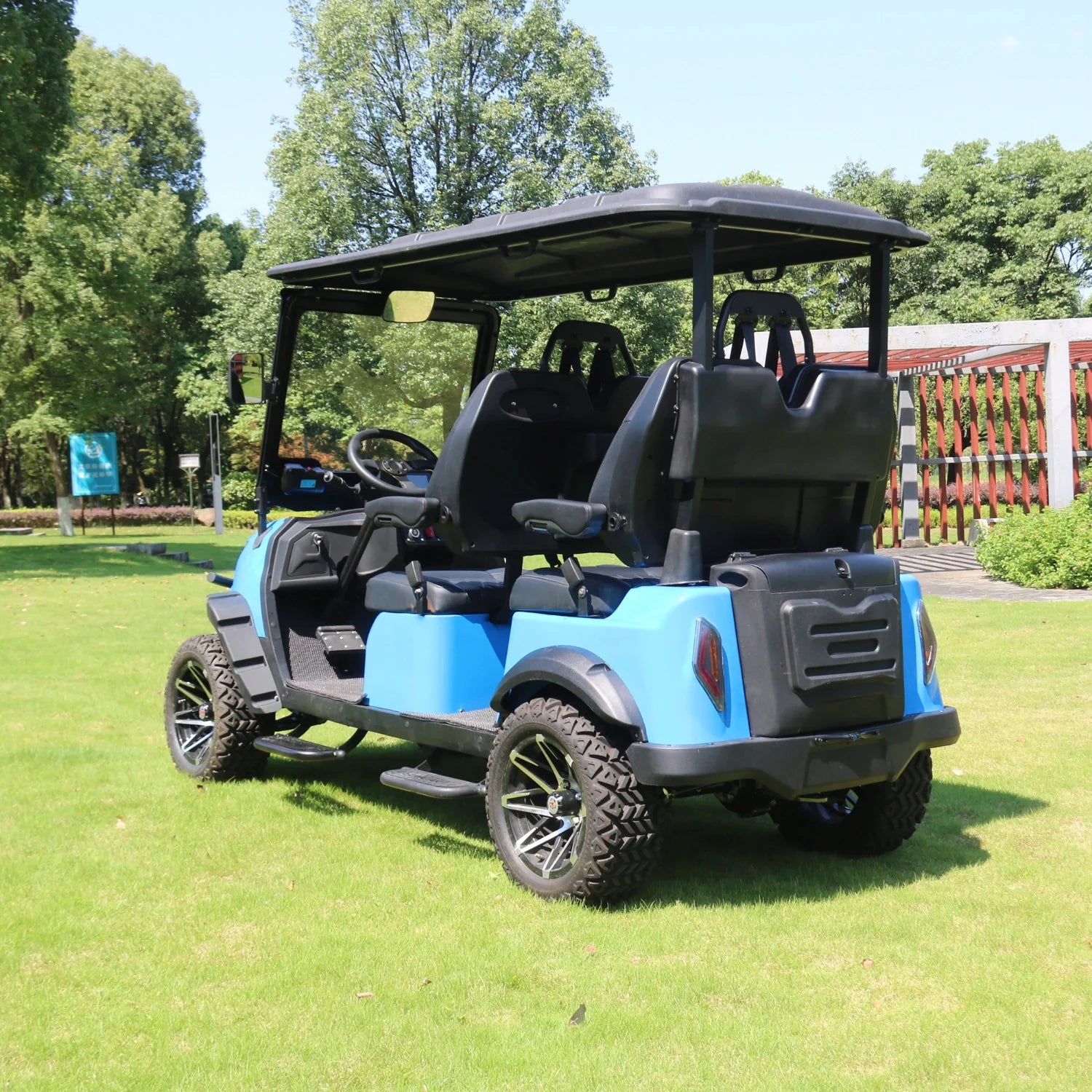 Blue and black golf cart on a grassy area with trees in the background