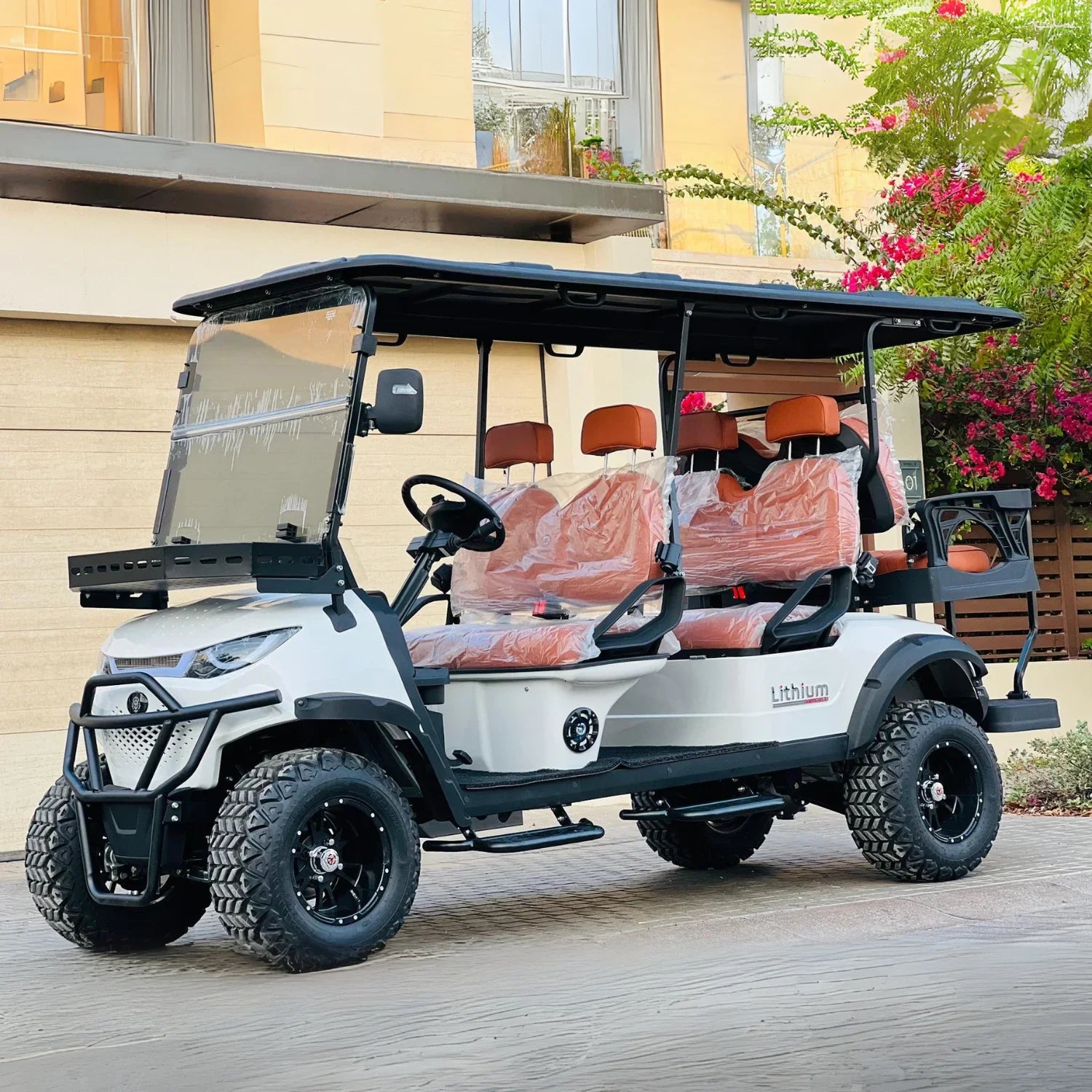 White and black golf cart with red seats on a wooden deck.