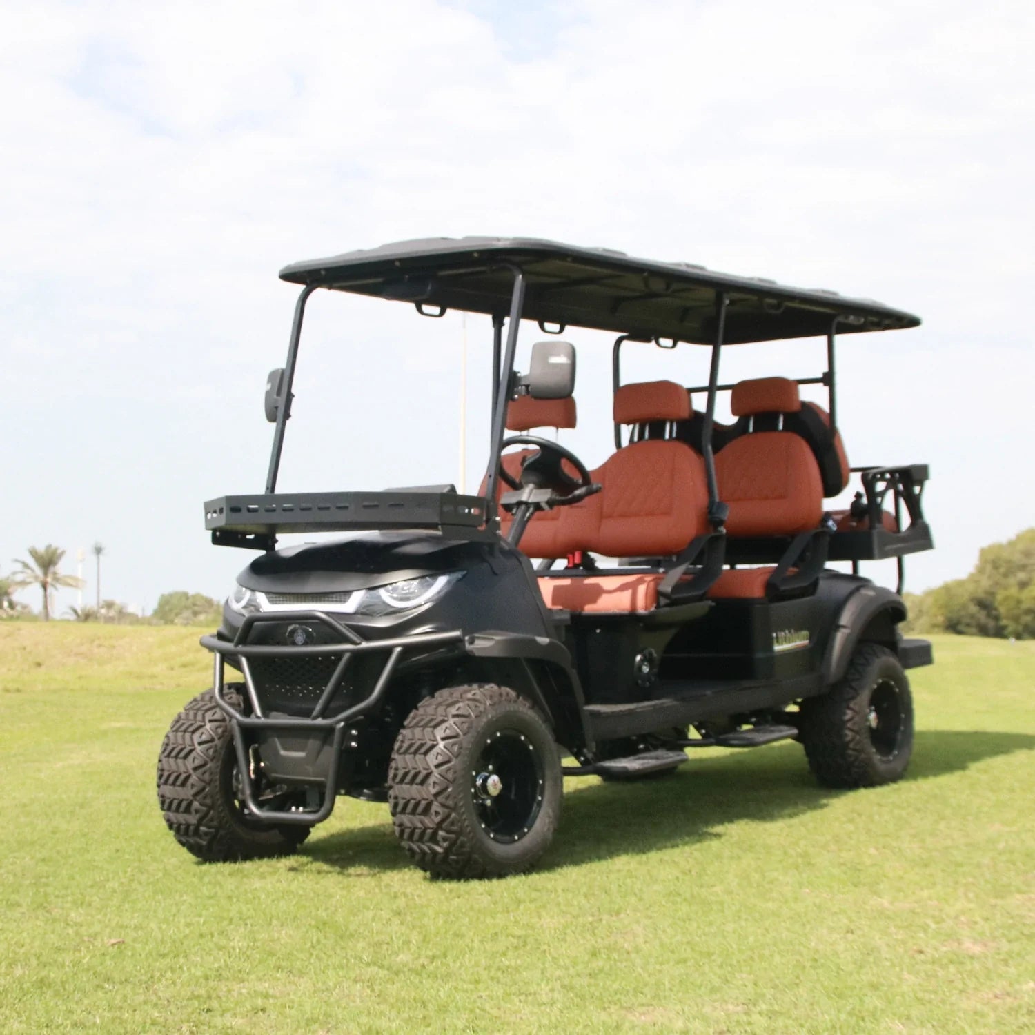 Black and red golf cart on a grassy field with trees in the background