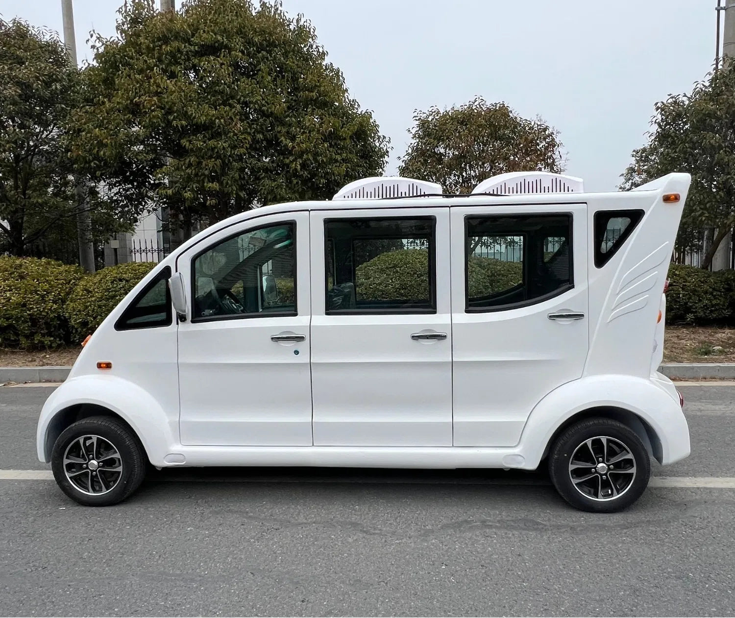 White electric vehicle on a road with trees in the background