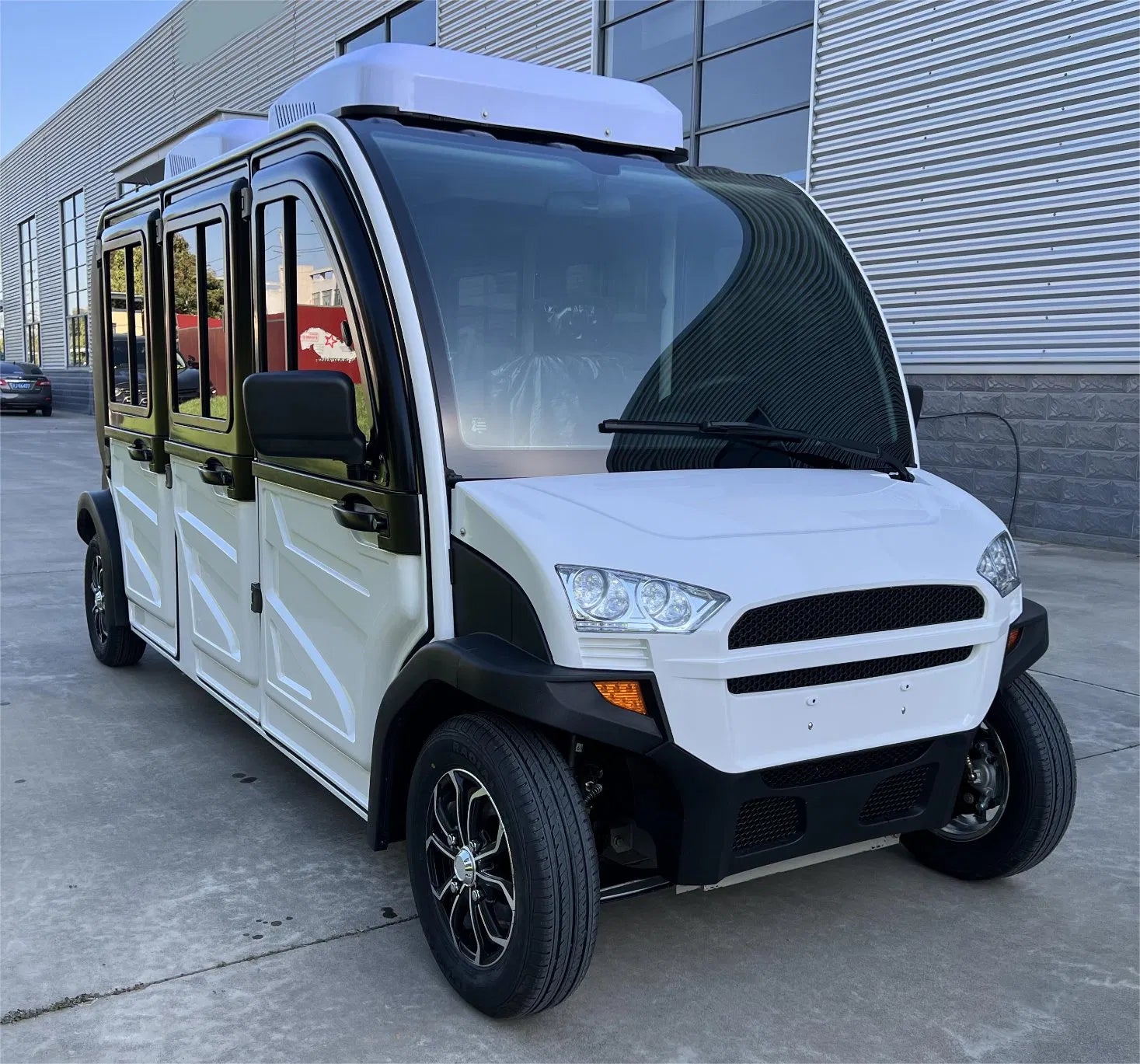 White and black electric shuttle vehicle parked in front of a building