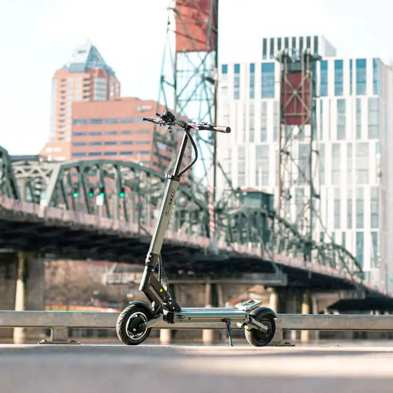 Electric scooter on a city street with buildings and a bridge in the background